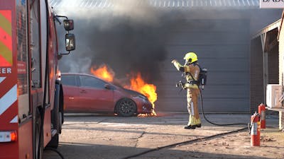 Vrouw rijdt brandende auto uit garage in Rijen